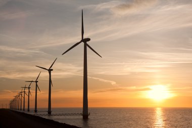 Wndturbines in the sea and a beautiful sunset clipart