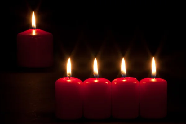 Conjunto de velas vermelhas queimando no escuro — Fotografia de Stock