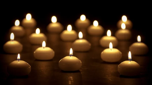 Grupo de velas acesas em um fundo preto com fo seletivo — Fotografia de Stock