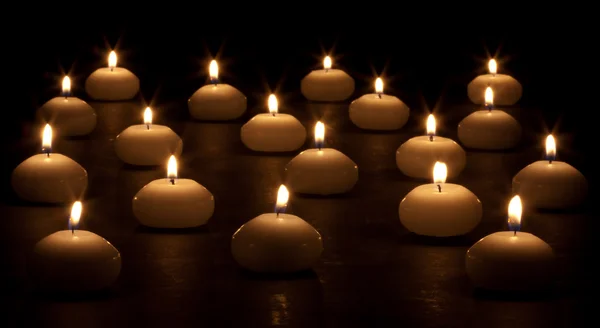 Grupo de velas acesas em um fundo preto — Fotografia de Stock