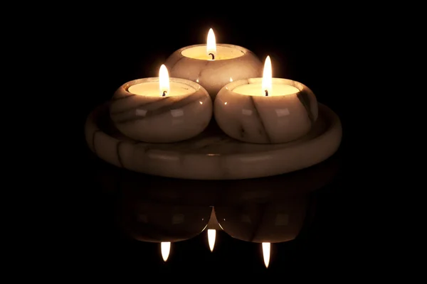 Декоративный подсвечник из мрамора с тремя огнями у черной бабы — стоковое фото