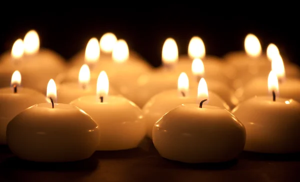 Группа горящих свечей на черном фоне с выборочным фоном — стоковое фото