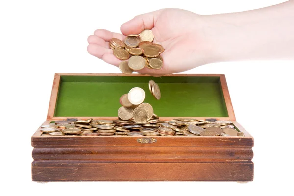 Mão soltando moedas em um baú do tesouro — Fotografia de Stock