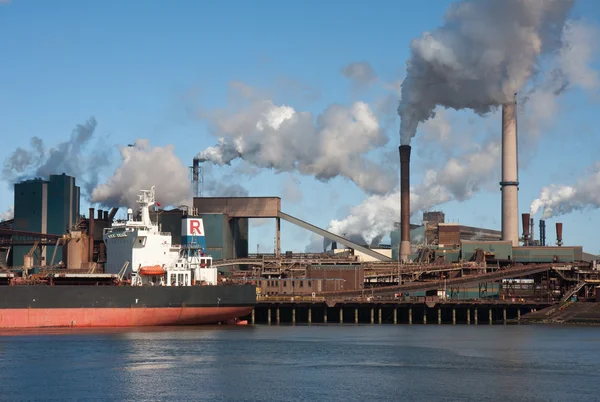 Steel factory with smokestacks and a big cargo ship — Stock Photo, Image