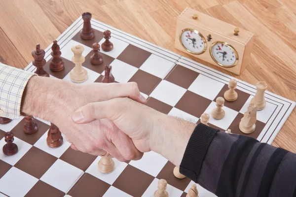 Shaking hands by a chess match — Stock Photo, Image