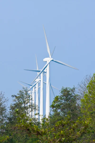 Fila de grandes turbinas eólicas atrás de árvores — Fotografia de Stock
