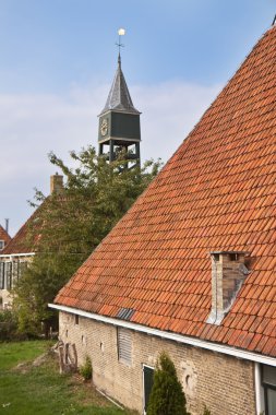 Old dutch historic farmhouse with churchtower behind it clipart