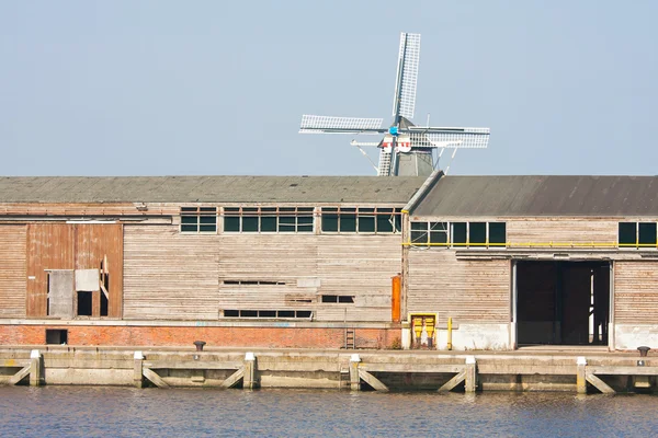 Porto olandese con un vecchio capannone di legno e un mulino a vento dietro di esso . — Foto Stock