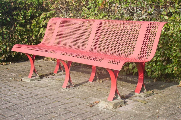 Red metal bench along a footpath in the park — Stock Photo, Image