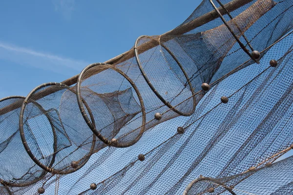 Рыбная сеть сохнет на солнце на фоне голубого неба — стоковое фото