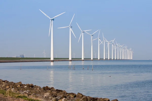 Windmühlen entlang der Küste, die sich in der ruhigen See spiegeln. — Stockfoto