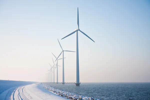 Row of snowy windmills standing in Dutch sea disappearing in win — Stock Photo, Image