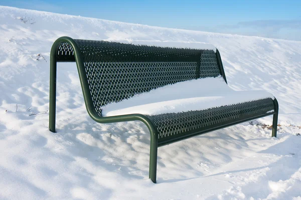 Зеленая железная скамейка, покрытая снегом в зимнее время — стоковое фото