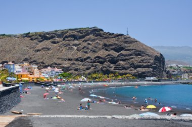 Sunbathing at the beach of Tazacorte, La Palma, Spain clipart