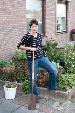 A woman is gardening in the front garden of her house