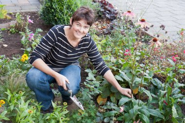 A woman is gardening in the front garden of her house