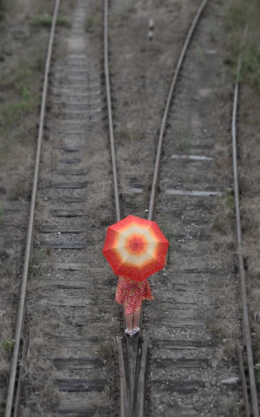 Κορίτσι με ομπρέλα σε σιδηροδρομικές γραμμές Royalty Free Εικόνες Αρχείου