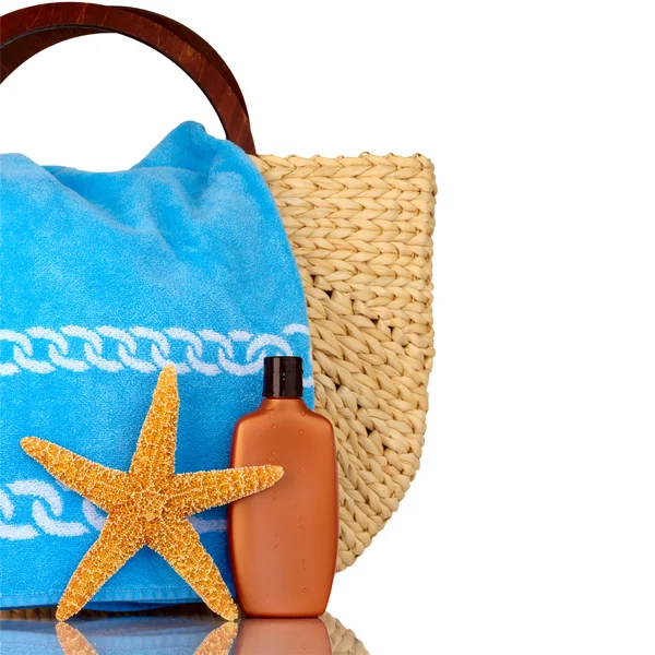 Hasır plaj çantası, deniz yıldızı WHI izole mavi havlu, güneş kremi Stok Fotoğraf
