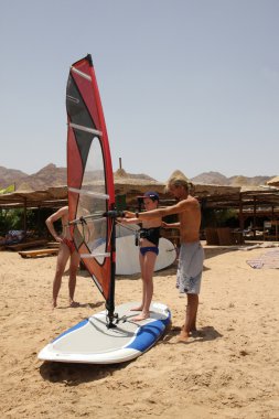 Teaching children windsurfing. clipart