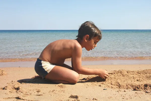Pojke att konstruera en siffra på stranden. — Stockfoto