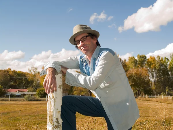 Eccentric man leaning to a fence post — Stock Photo, Image