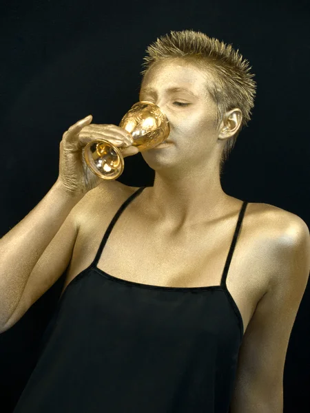 Gouden vrouw drinken uit een gouden goblet — Stockfoto