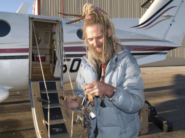 Eccentric senior man smiling by an aircraft holding key clipart