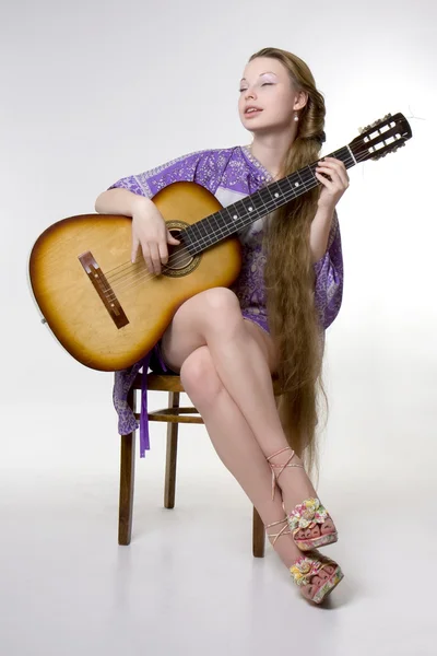 Красивая девушка, которая играет на гитаре — стоковое фото