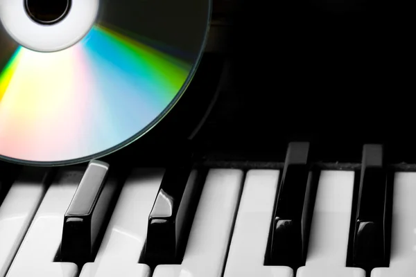 CD-диск, лежащий на клавишах пианино — стоковое фото