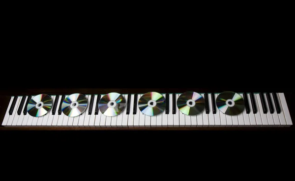 CD-диск, лежащий на клавишах пианино — стоковое фото