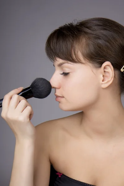 Красивая девушка, которая делает макияж кисти — стоковое фото