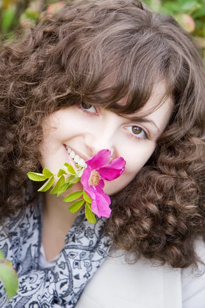 Meisje op een achtergrond van bloemen en fruit dogrose — Stockfoto