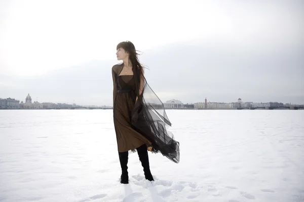 Chica contra un fondo de nieve y la ciudad . — Foto de Stock