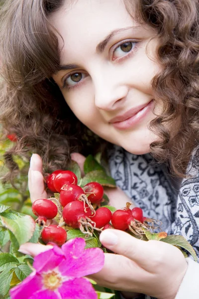 Chica sobre un fondo de flores y frutas escaramujo — Foto de Stock
