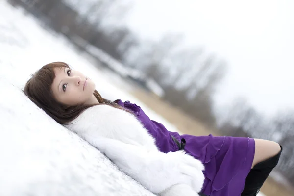 Flicka som ligger på snön i klänning — Stockfoto