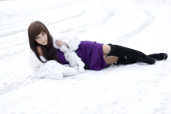 Menina que se deita na neve no vestido — Fotografia de Stock