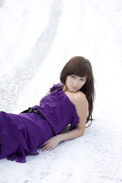 Mädchen, das im Kleid auf dem Schnee liegt — Stockfoto