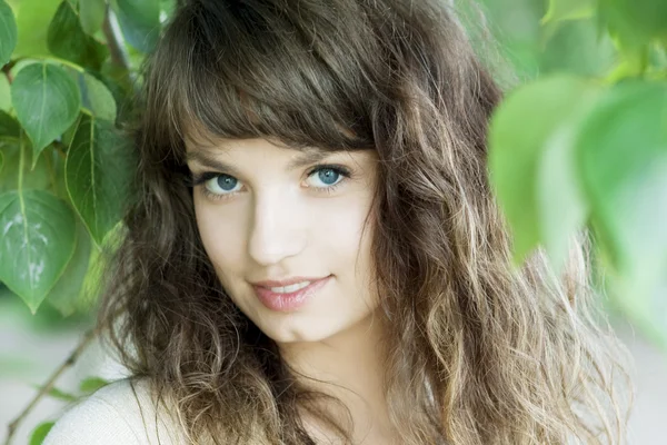 Chica con ojos azules en el follaje —  Fotos de Stock