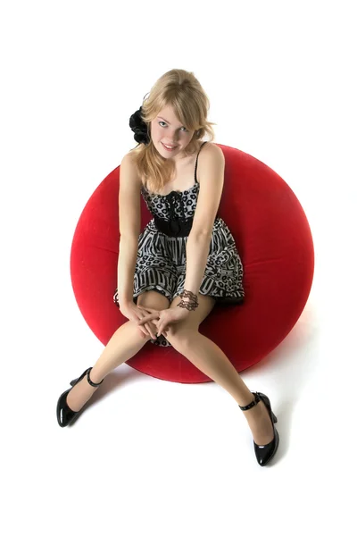 Ragazza bionda, che siede su una sedia rossa Fotografia Stock