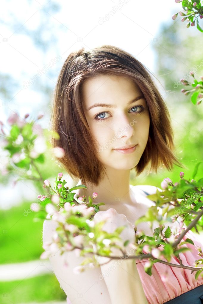 Beautiful girl among the blooming trees