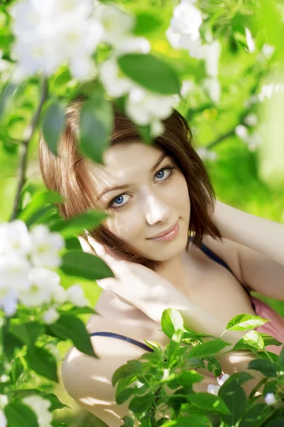 Flicka på en bakgrund av blommande blommor — Stockfoto