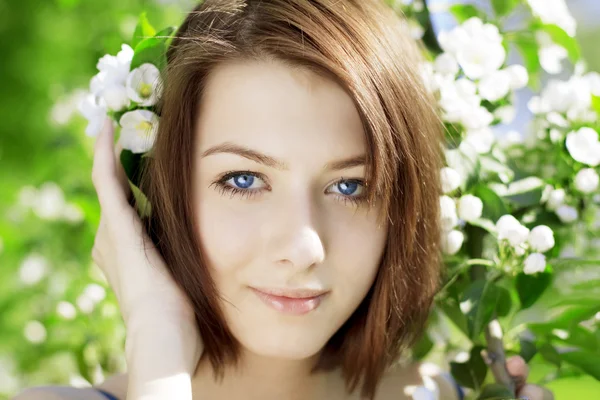 Meisje op de achtergrond van een bloeiende bloemen — Stockfoto