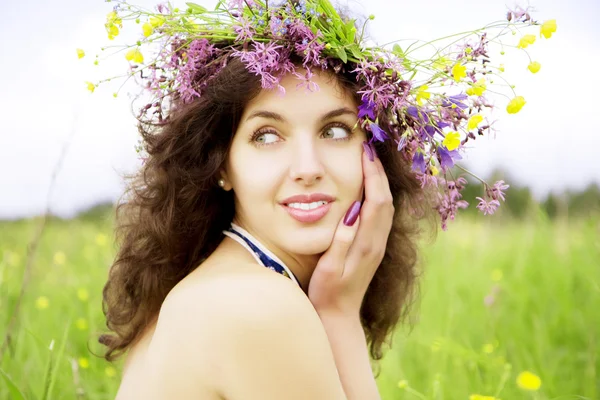 Chica con una corona de flores silvestres en el campo —  Fotos de Stock