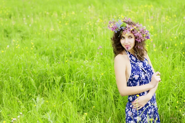Chica con una corona de flores silvestres en el campo — Foto de Stock