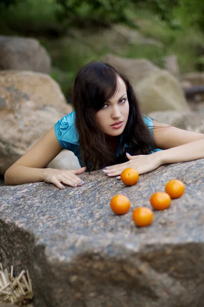 Schönes junges Mädchen mit den Mandarinen in der Natur — Stockfoto