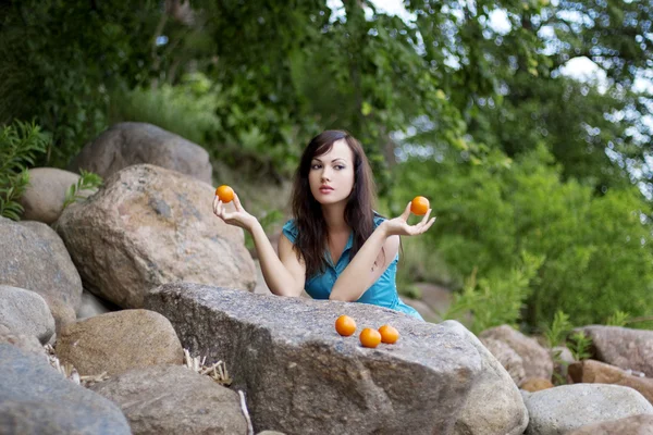 Mooi meisje met de mandarijnen in de natuur — Stockfoto