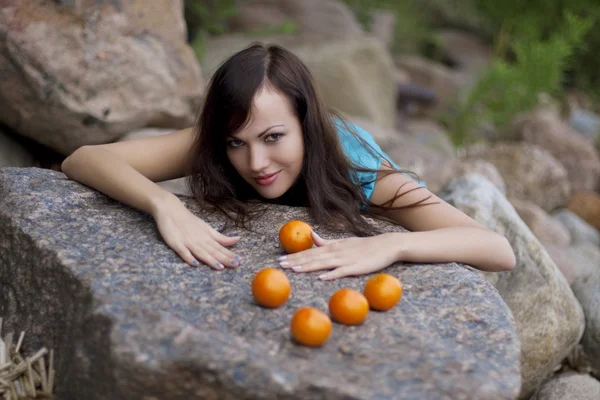 Schönes junges Mädchen mit den Mandarinen in der Natur — Stockfoto