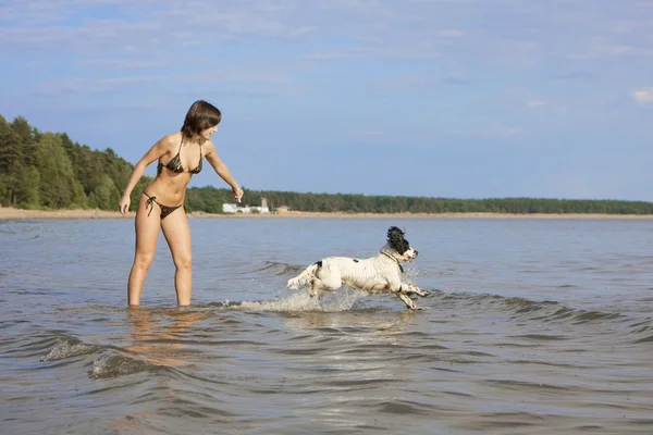 Piękna szczupła dziewczyna gra na plaży z psem — Zdjęcie stockowe