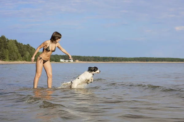 Bella ragazza snella che gioca sulla spiaggia con un cane — Foto Stock