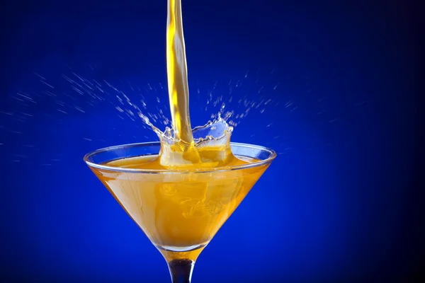 Splash de suco de laranja em um fundo azul — Fotografia de Stock